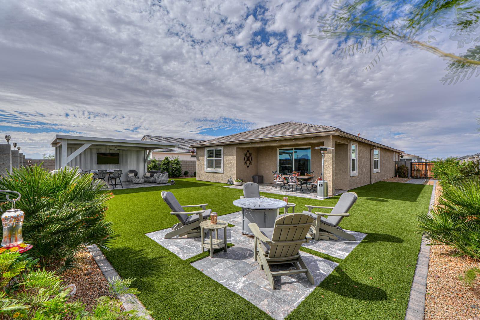 Backyard remodel with artificial turf, fire pit seating area, and covered patio